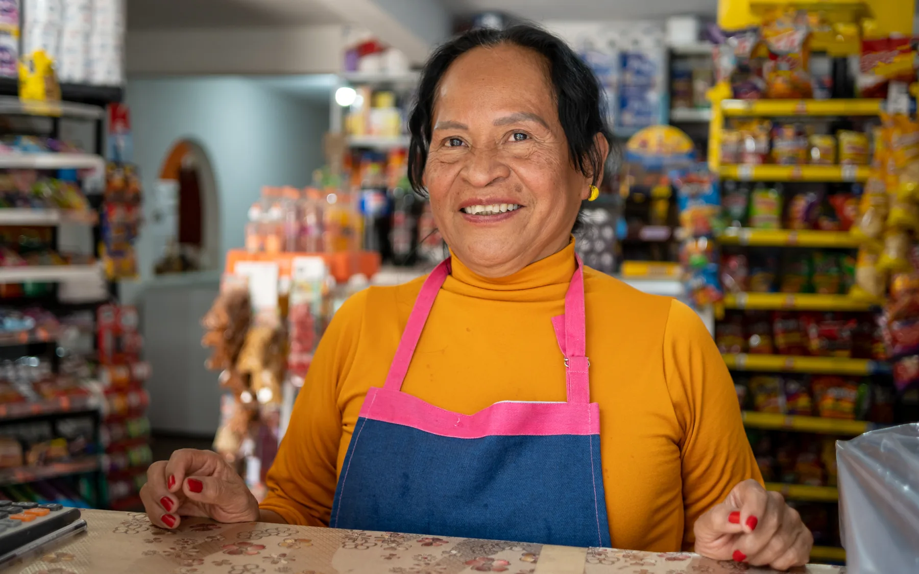 Woman wearing an apron behind a grocery store counter